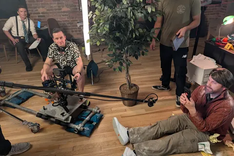 Brian rides the dolly between setups on a detective’s office set