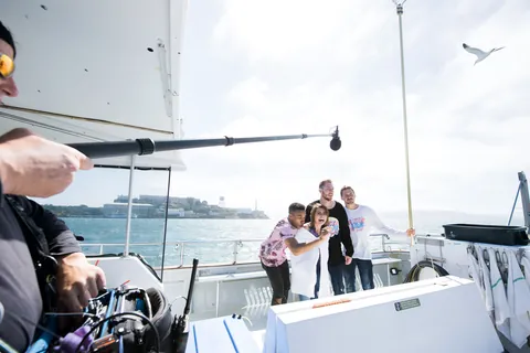 A boom operator recording the hosts on a boat in San Francisco Bay